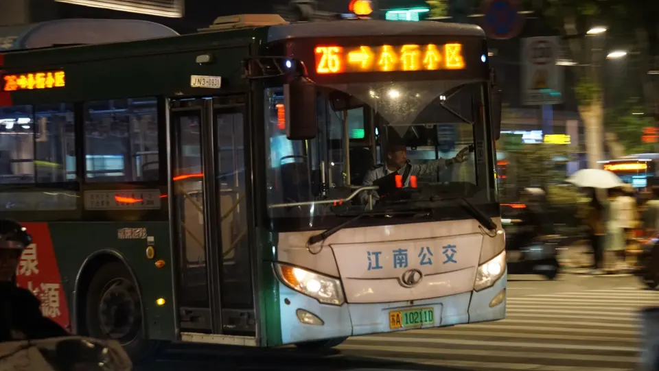 Grüner Linienbus bei Nacht in Nanjing mit leuchtender chinesischer Zielanzeige